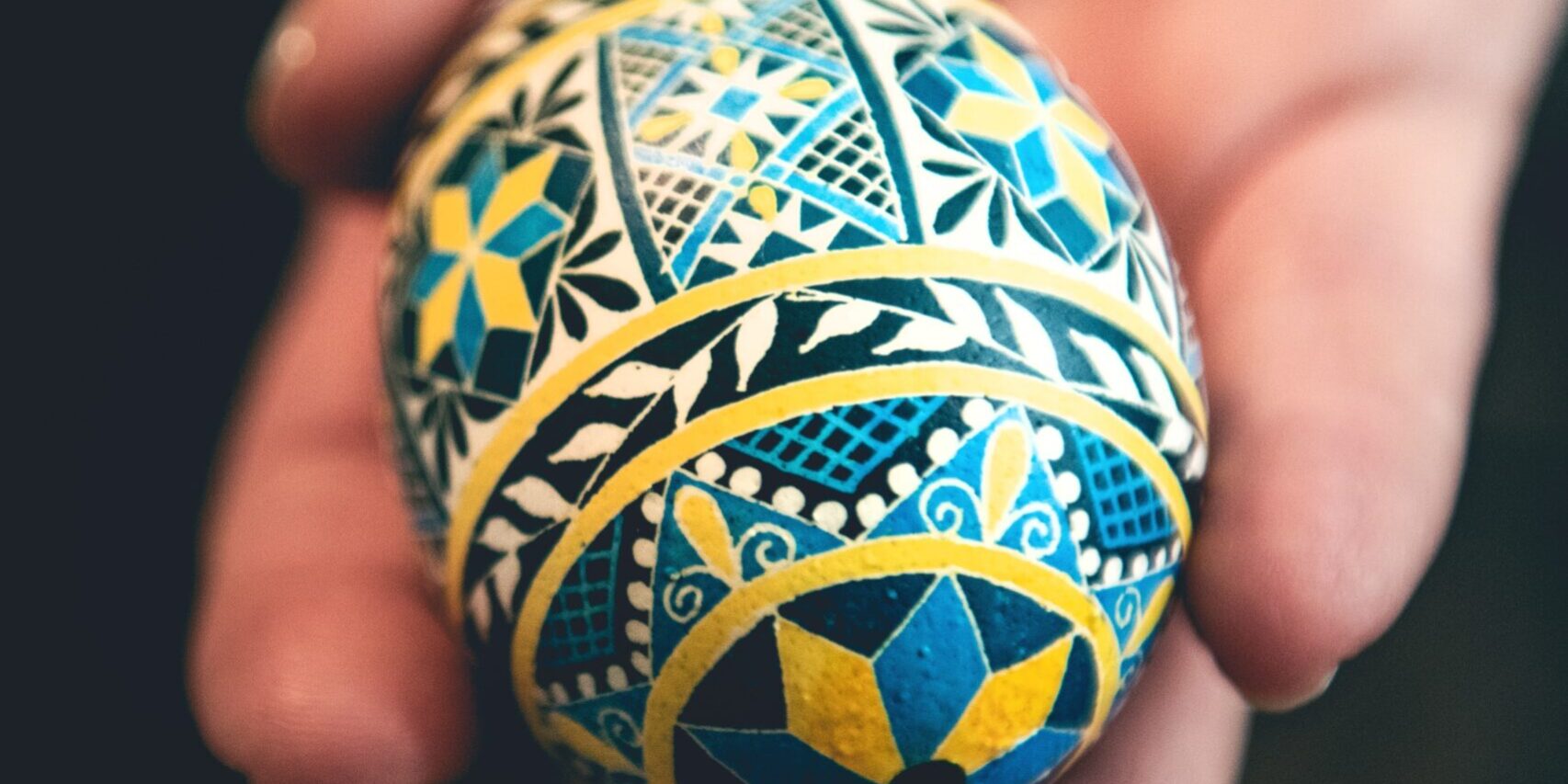 a person holding a painted egg in their hand